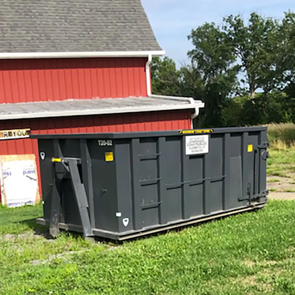 A commercial dumpster rental sitting on the grass in front of a barn near Akron, Ohio.