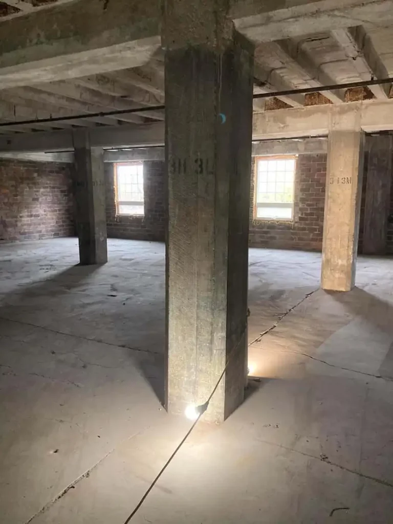 A spacious empty room with polished concrete floors and sturdy pillars.