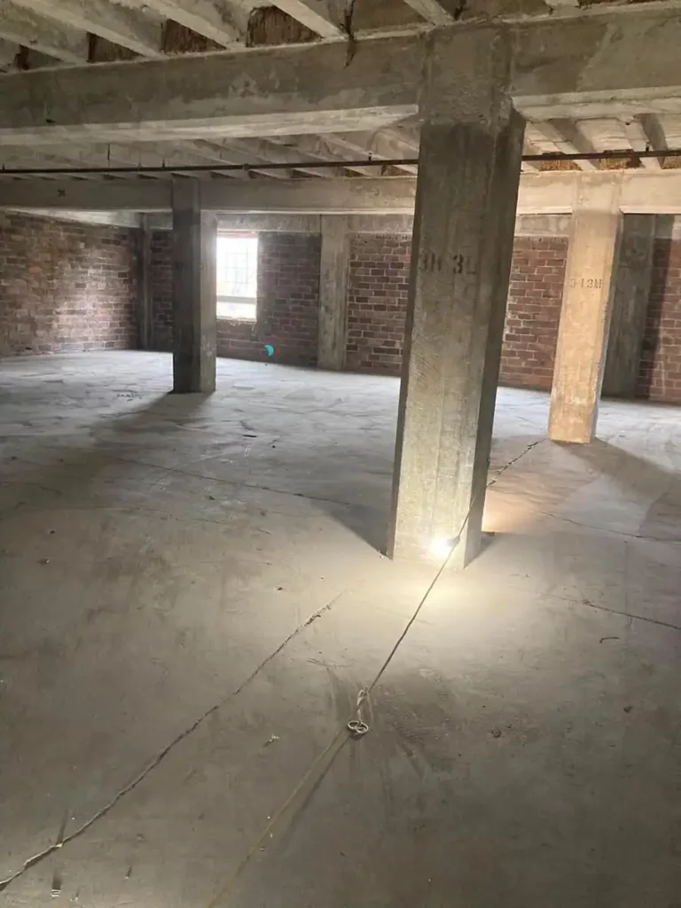 A vacant room with concrete floors and brick walls, in need of clean-out services in Akron.